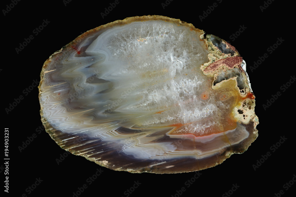 A cross-section of agate. Micro-stalactite agate with quartz-agate fill. Multicolored silica bands colored with metal oxides are visible. Origin: Rudno near Krakow, Poland. A cross-section of agate. Micro-stalactite agate with quartz-agate fill. Multicolored silica bands colored with metal oxides are visible. Origin: Rudno near Krakow, Poland.