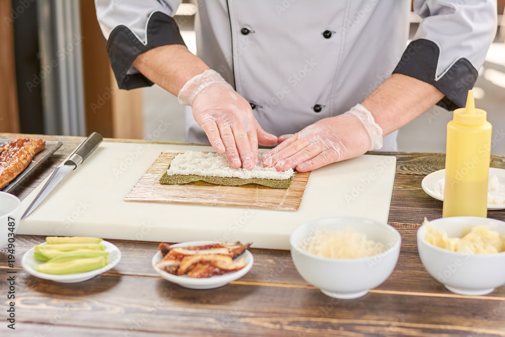 Chef hands touching white rice. Chef at professional kitchen preparing sushi roll. Japanese cook at work, kitchen.