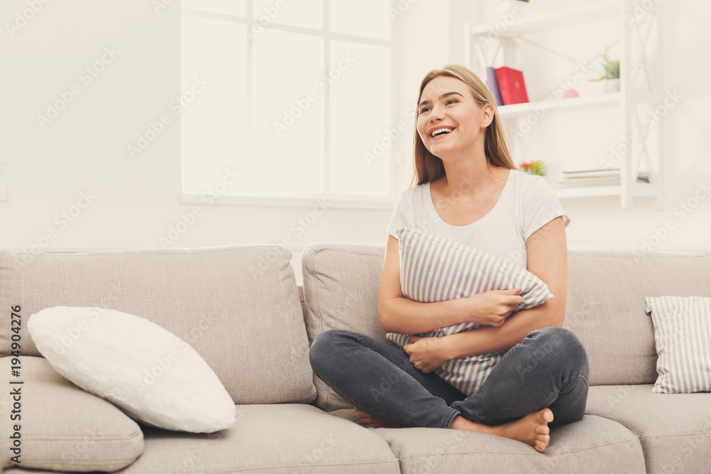 Young smiling woman sitting on beige couch