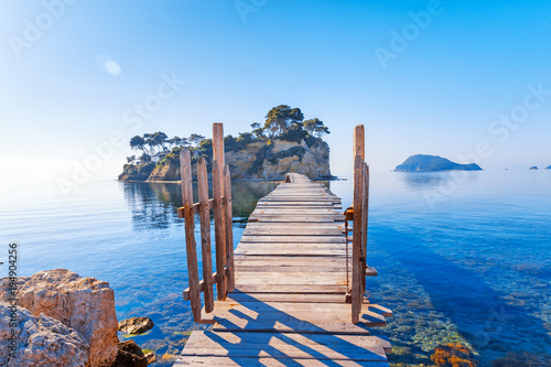 Greece. Picturesque wooden pedestrian Bridge to the small atoll island, view from great Greek Zante or Zakinthos island. Beautiful morning scenery in sunny spring day. photo