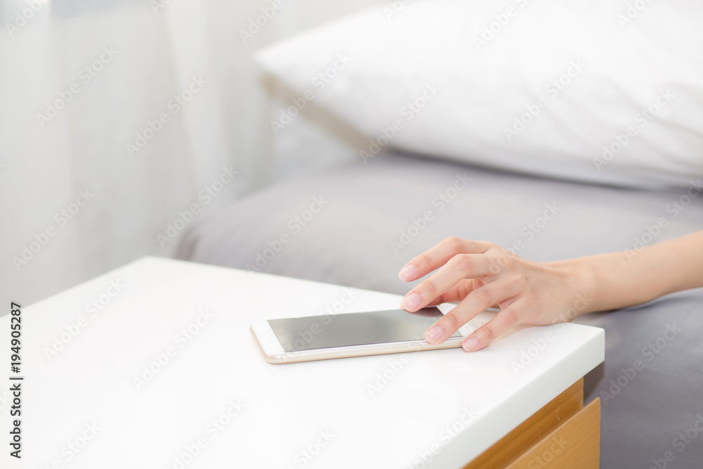 hand of woman turn off alarm on call mobile phone while wake up after sleep relax in good morning at bedroom. hand of woman turn off alarm on call mobile phone while wake up after sleep relax in good morning at bedroom.