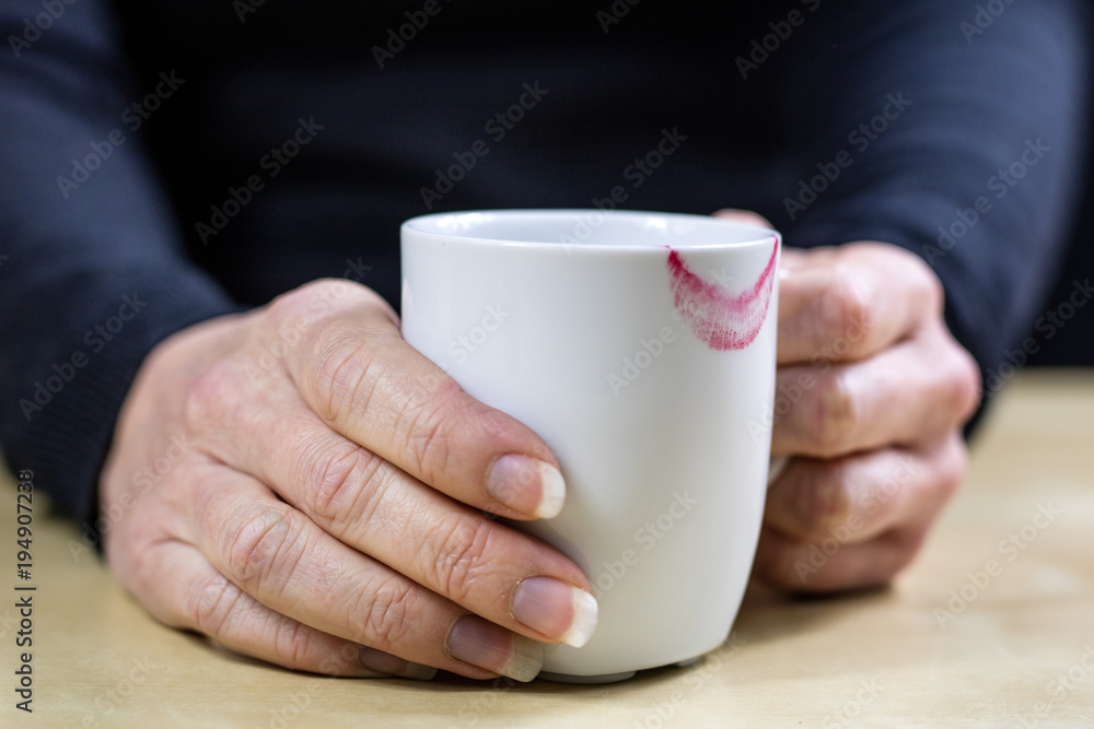Empty white mug with gloves. Hands in warm gloves holding a china mug on a wooden kitchen table. Empty white mug with gloves. Hands in warm gloves holding a china mug on a wooden kitchen table.