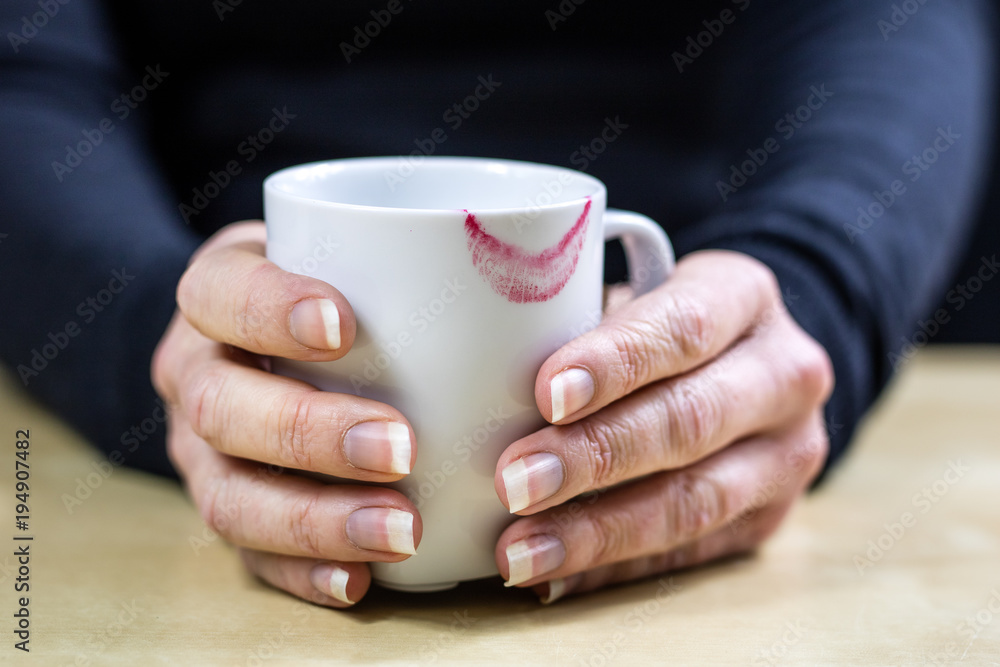 Empty white mug with gloves. Hands in warm gloves holding a china mug on a wooden kitchen table. Empty white mug with gloves. Hands in warm gloves holding a china mug on a wooden kitchen table.
