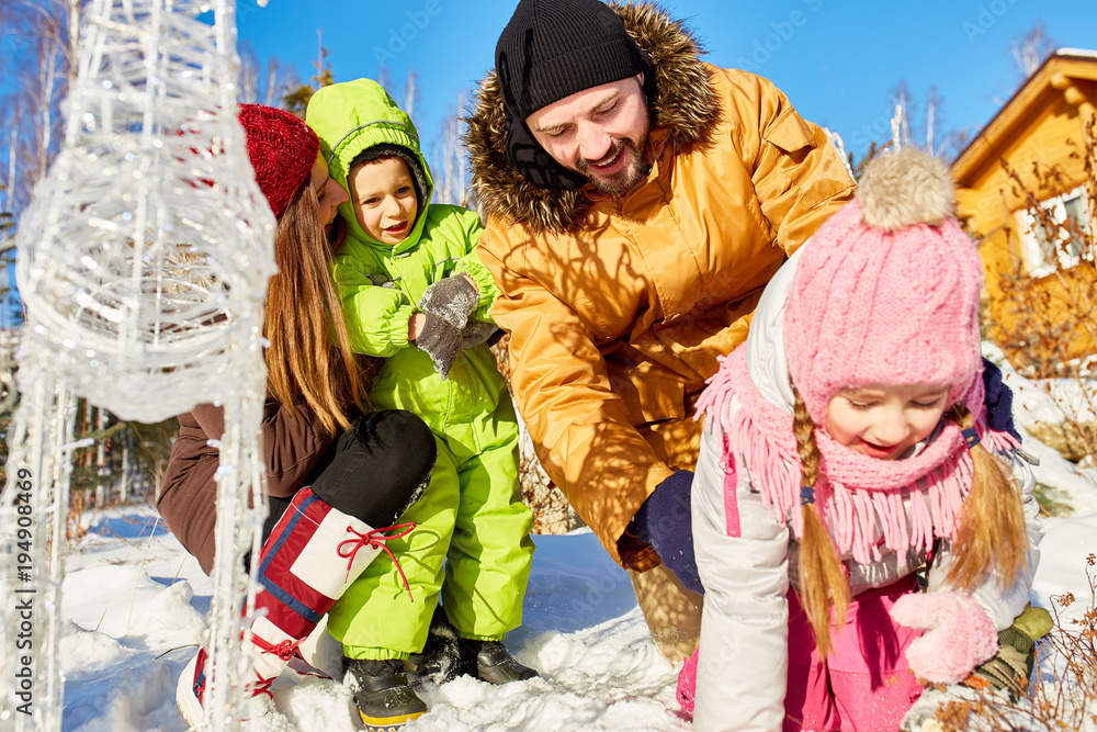 Low angle view of young Caucasian couple playing with their children outdoors on sunny winter afternoon