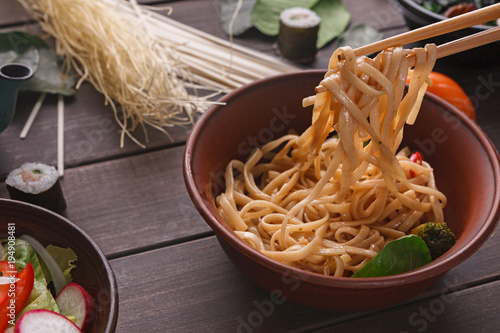 Bowl of rice noodles with soy souce on wooden background