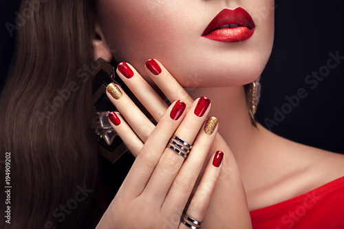 Beautiful woman with perfect make-up and red and golden manicure wearing jewellery