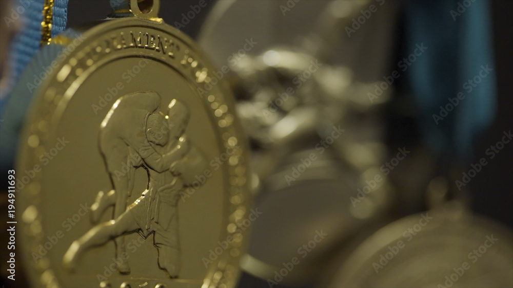 Close up of the golden medals. A rugged gold medal setup majestically against grey background. Gold medals before handing to champions. Gold, silver and bronze medals close up
