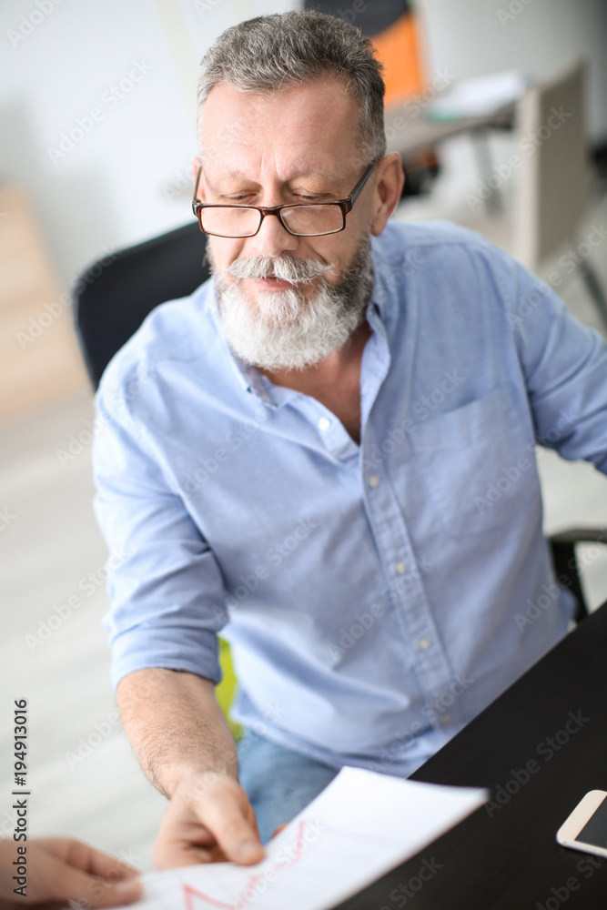 Senior man working with documents at table in office Senior man working with documents at table in office