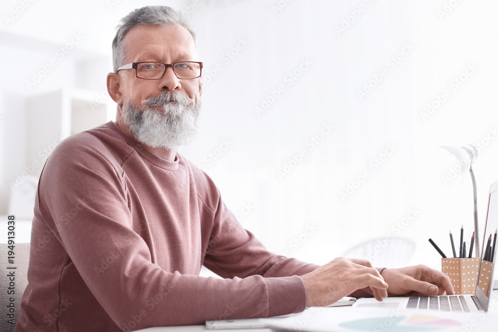 Fototapeta premium Senior man working with laptop at table in office
