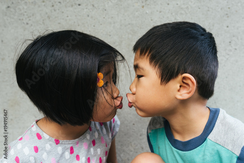 Asian American toddlers getting ready to kiss each other with puckered lips