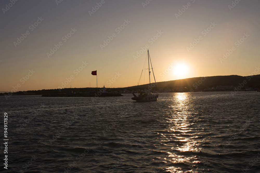 View of a sailboat, Aegean sea and landscape in Cunda (Alibey) island at sunset.