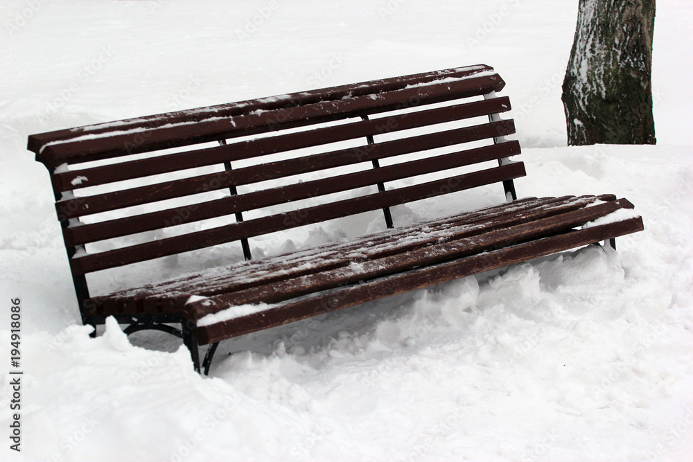 Bench in a park covered with snow in winter