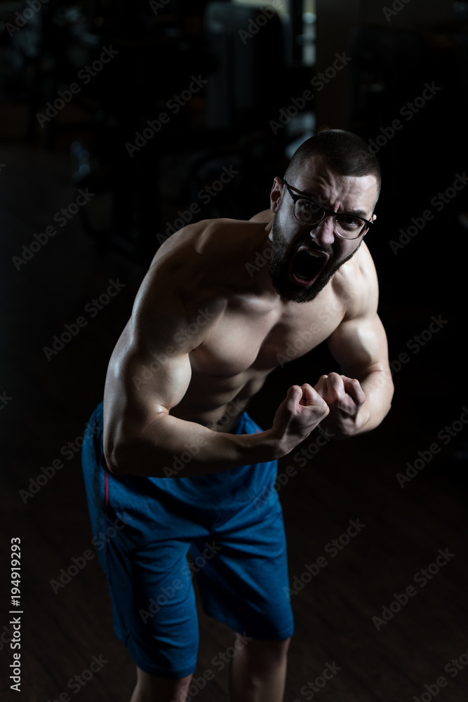 Young Bodybuilder Wearing Eyeglasses Flexing Muscles