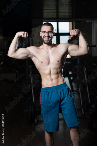 Muscular Geek Man Flexing Muscles In Gym