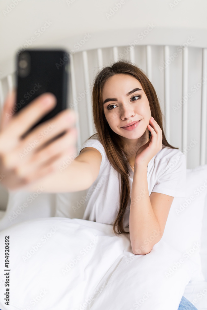 Beautiful girl making selfie in the bed. Beautiful girl making self on the bed at home. Selfie in the morning Beautiful girl making selfie in the bed. Beautiful girl making self on the bed at home. Selfie in the morning