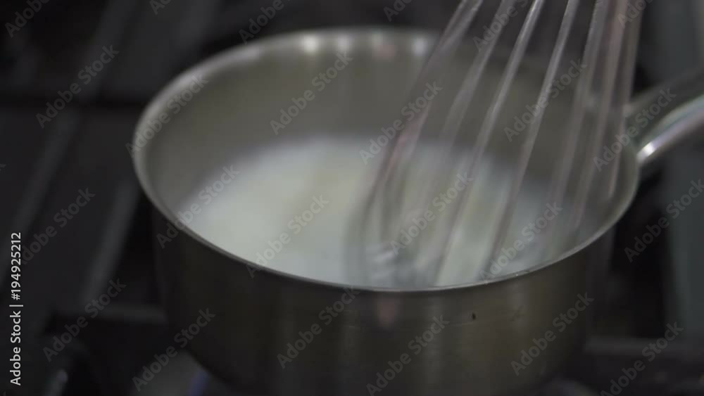 Closeup chef's hands stirring coconut milk for fish soup schrimp soup in saucepan Closeup chef's hands stirring coconut milk for fish soup schrimp soup in saucepan
