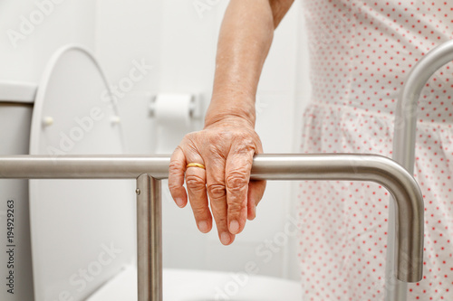 Konstfotografi Elderly woman holding on handrail in toilet.