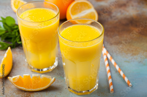 Two glasses with freshly squeezed orange juice and mint on an old rusty blue background