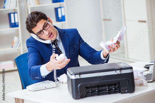 Obraz na plátně Businessman angry at copying machine jamming papers