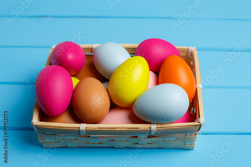 Easter eggs in the basket on blue wooden background photo