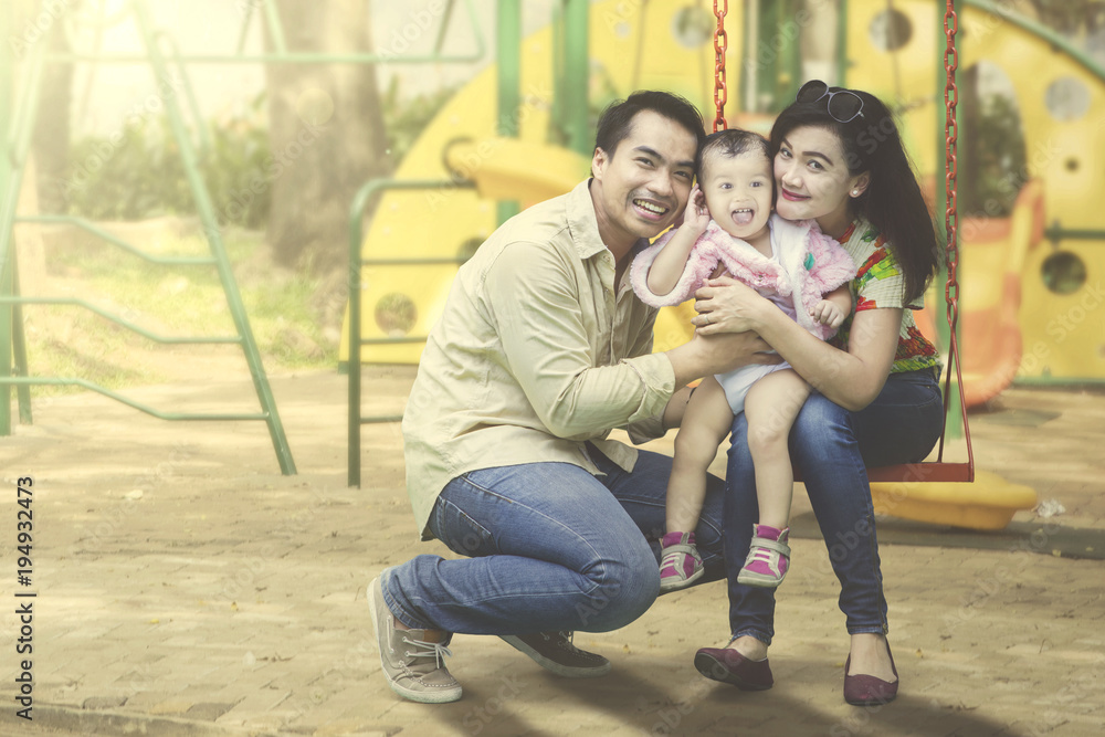 Fototapeta premium Young family posing together at playground.