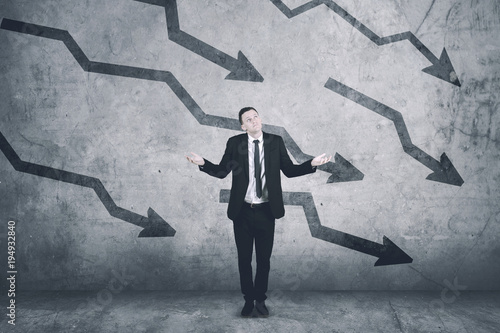 Canvas-taulu Confused caucasian businessman with declining charts on the wall
