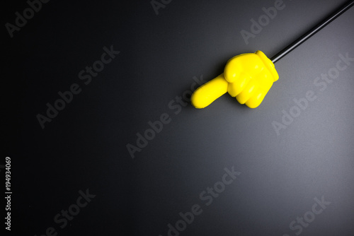 Yellow plastic hand pointing on black background with copy space.