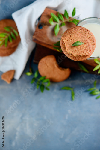 Homemade cookies with tiny green leaves decor on a stone background with wooden boxes and white linen napkin. Spring baking flat lay with copy space.