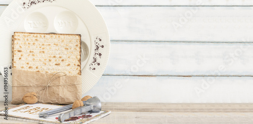 Pack of matzah or matza, Passover Haggadah, red kosher wine and white passover seder plate on a vintage wood background. Jewish Passover holiday composition with copy space.