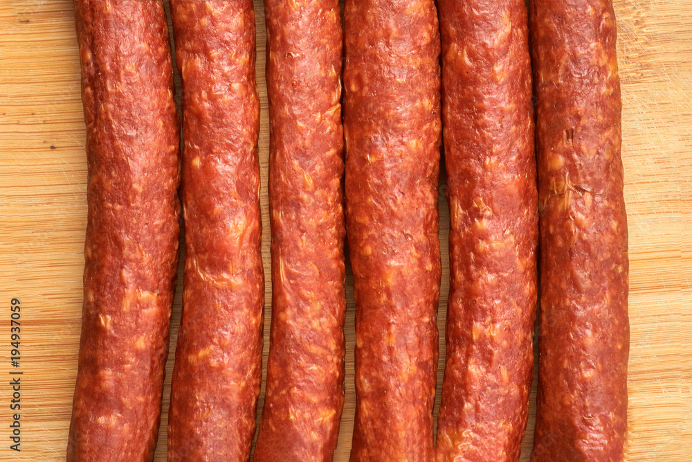 Thin smoked sausage on a wooden background. Close-up. Thin smoked sausage on a wooden background. Close-up.
