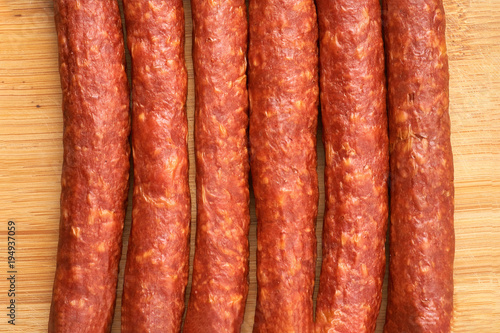 Thin smoked sausage on a wooden background. Close-up.