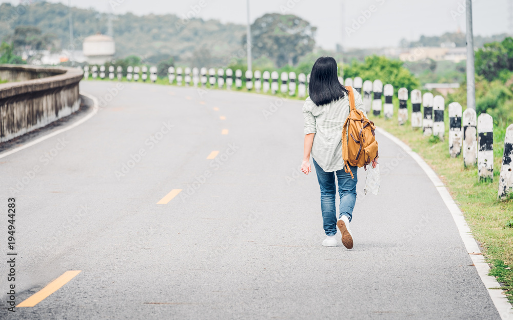 Traveler with backpack holding map and get lost,asian woman backpacker standing on road and looking forward to see way,freedom journey concept,hitchhiker travel.
