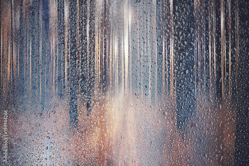 glass wet autumn background  rain in the park glass wet surface with reflection  rain drops on the drenched window glass  background window in the autumn park  autumnal rainy landscape blurred