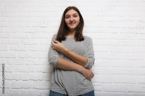 A young pretty smiling girl against a white loft-style brick wall. She looks at the viewer. Copy space. photo