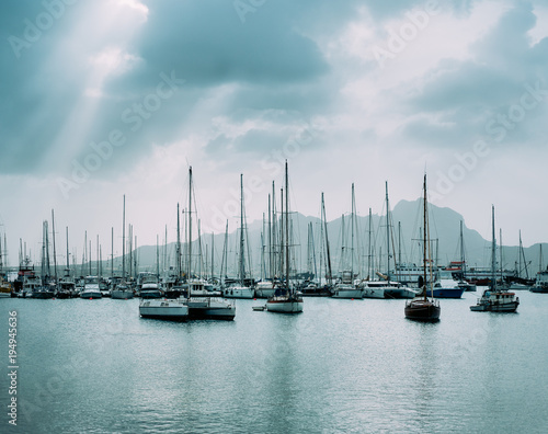 Sailboats and pleasure boats in the porto grande bay of the historic city Mindelo. Clodscape with Sunrays photo