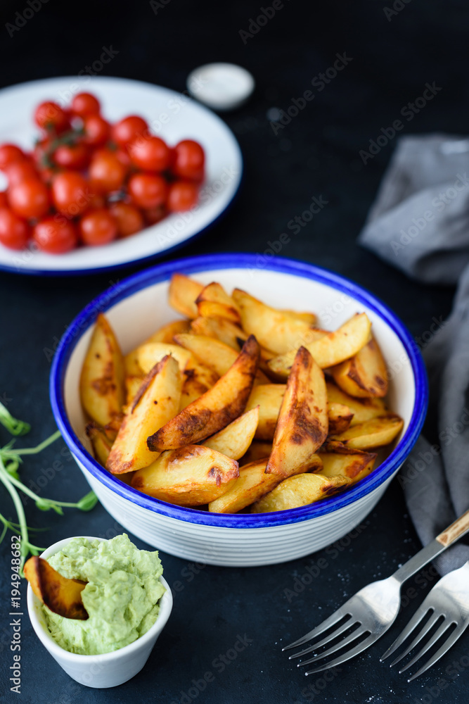 Roasted potatoes with spices in a bowl on dark background. Selective focus Roasted potatoes with spices in a bowl on dark background. Selective focus