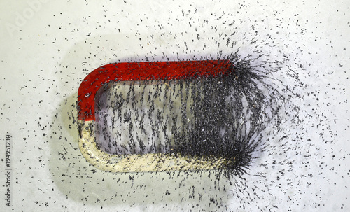 The lines of forces around a magnet shown, with iron chips spread on a glass plate that rests on the magnet. photo