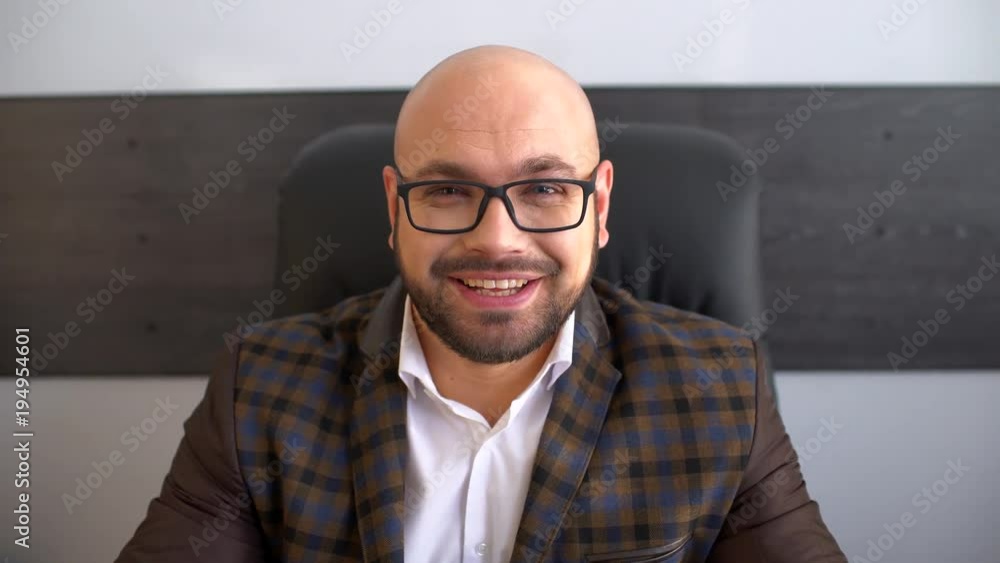 Young businessman at the workplace is looking at the camera and smiling. 4 k Young businessman at the workplace is looking at the camera and smiling. 4 k
