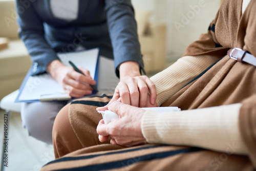 Close up of female psychologist holding hand of senior woman during therapy session, copy space photo