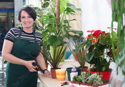 portrait of woman florist in apron and tool in flower shop photo