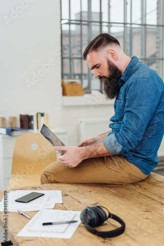 Bearded businessman sitting perched on a table