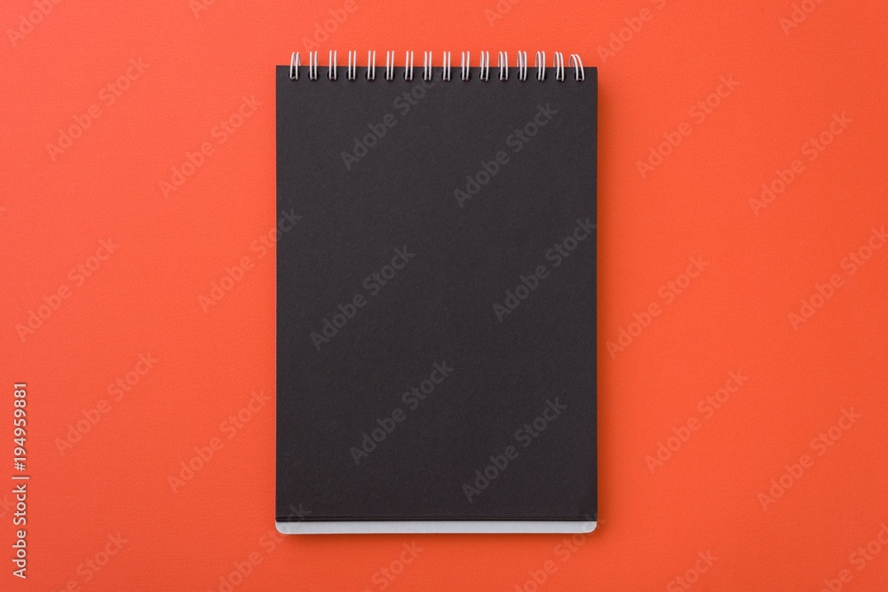Top view of open spiral blank black notebook l on orange desk background, Place for your text Top view of open spiral blank black notebook l on orange desk background, Place for your text