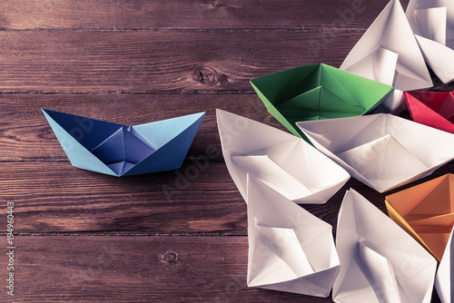 Business leadership concept with white and color paper boats on 