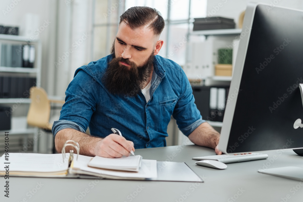 Bearded man working in front of monitor at office Bearded man working in front of monitor at office