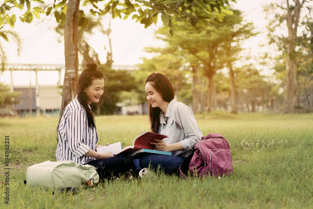 Young women together study reading book in university and knowledge at outside or park campus relaxing smile in summer season