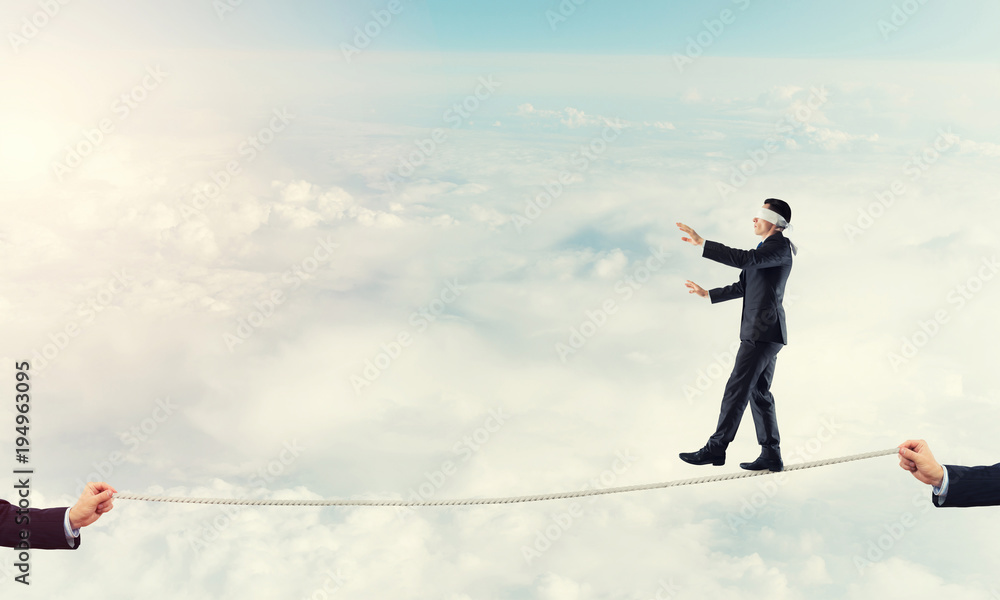 Business concept of risk support and assistance with man balancing on rope Business concept of risk support and assistance with man balancing on rope