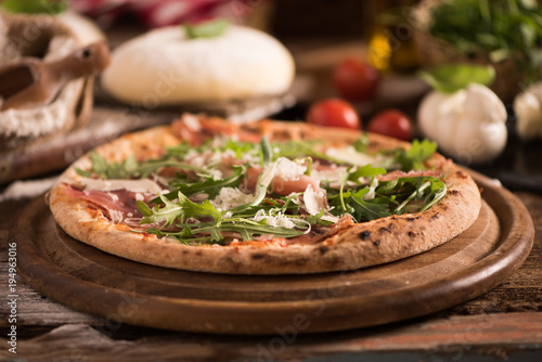 Italian Pizza with rocket salad on wooden table