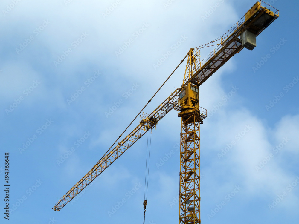 Construction crane against the cloudy blue sky