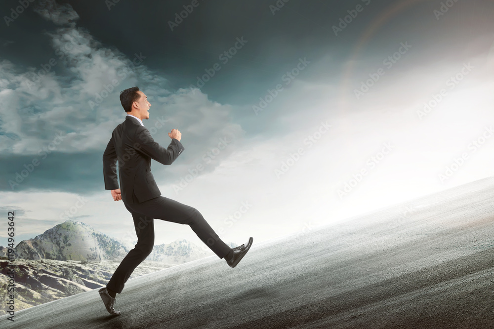 Attractive asian businessman running to uphill mount Attractive asian businessman running to uphill mount