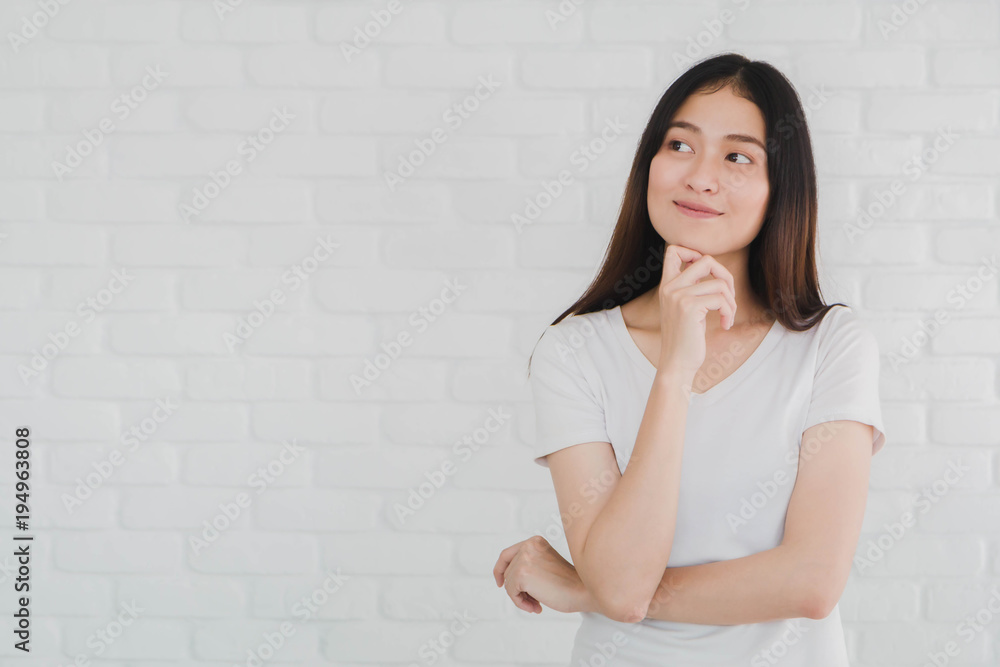 Happy beautiful Asian woman gesturing with hands and thinking in a white brick wall background. Happy beautiful Asian woman gesturing with hands and thinking in a white brick wall background.